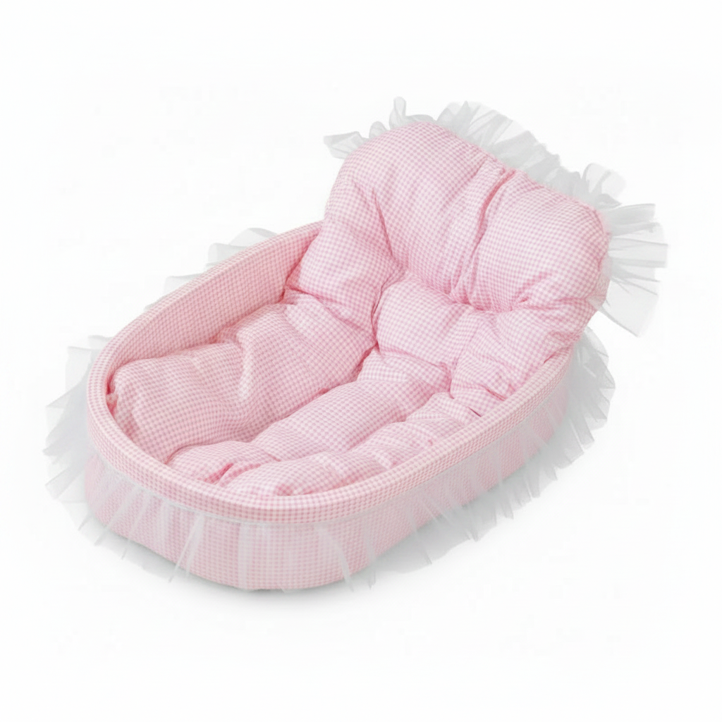 Blush pink gingham oval pet bed with tufted bolster backrest and sheer white lace ruffle trim, angled product shot on white background