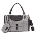 A black and white houndstooth pet carrier with black leather trim, dual top handles, a front flap pocket, and a matching small pouch, shown on a plain white background.