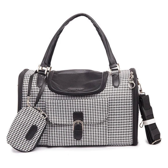 A black and white houndstooth pet carrier with black leather trim, dual top handles, a front flap pocket, and a matching small pouch, shown on a plain white background.