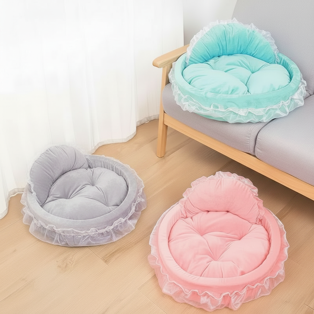 Three round ruffle lace pet beds in silver grey, pink, and mint teal displayed in a bright minimalist room scene with wood floor, grey sofa, and sheer white curtain