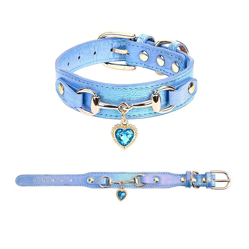 Holographic blue metallic pet collar with gold snaffle-bit hardware and blue crystal heart charm pendant, shown in close-up and full-length views on a white background