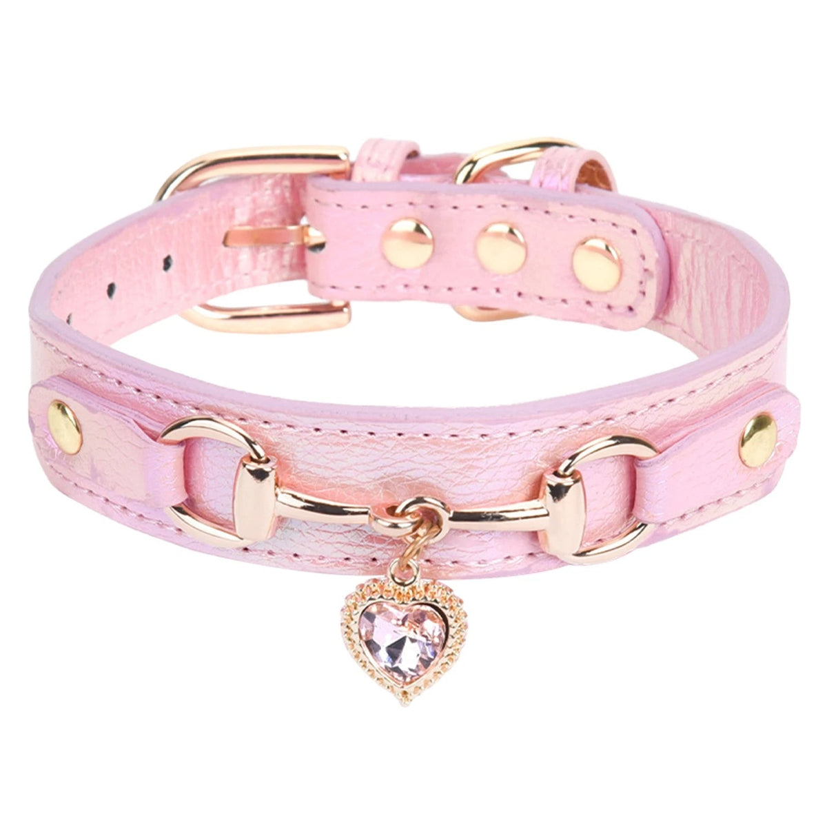 Pink leather pet collar with rose gold snaffle-bit hardware, gold stud accents, and a pink crystal heart charm pendant, shown in close-up detail on a white background