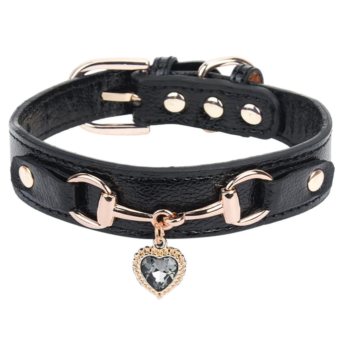 Black leather pet collar with rose gold snaffle-bit hardware, gold stud accents, and a grey crystal heart charm pendant, shown in close-up detail on a white background