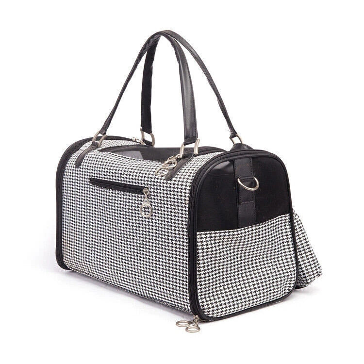A small houndstooth dog carrier bag with black faux-leather trim, dual top handles, a front zip pocket, and a detachable shoulder strap, shown on a plain white background.