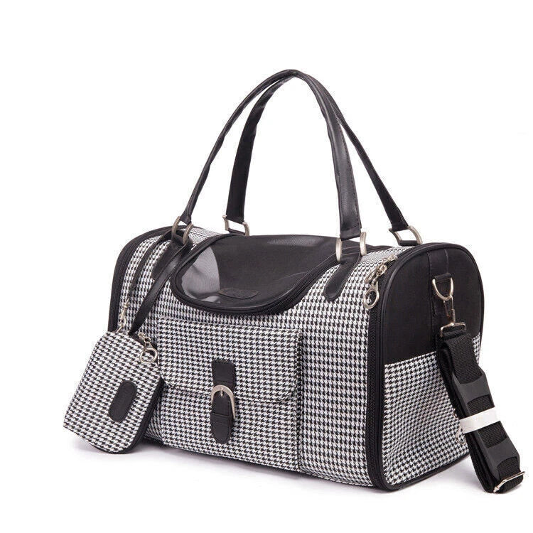 A black and white houndstooth pet carrier duffel bag with black faux-leather handles, a clear window, and a matching zippered pouch, shown on a white background.