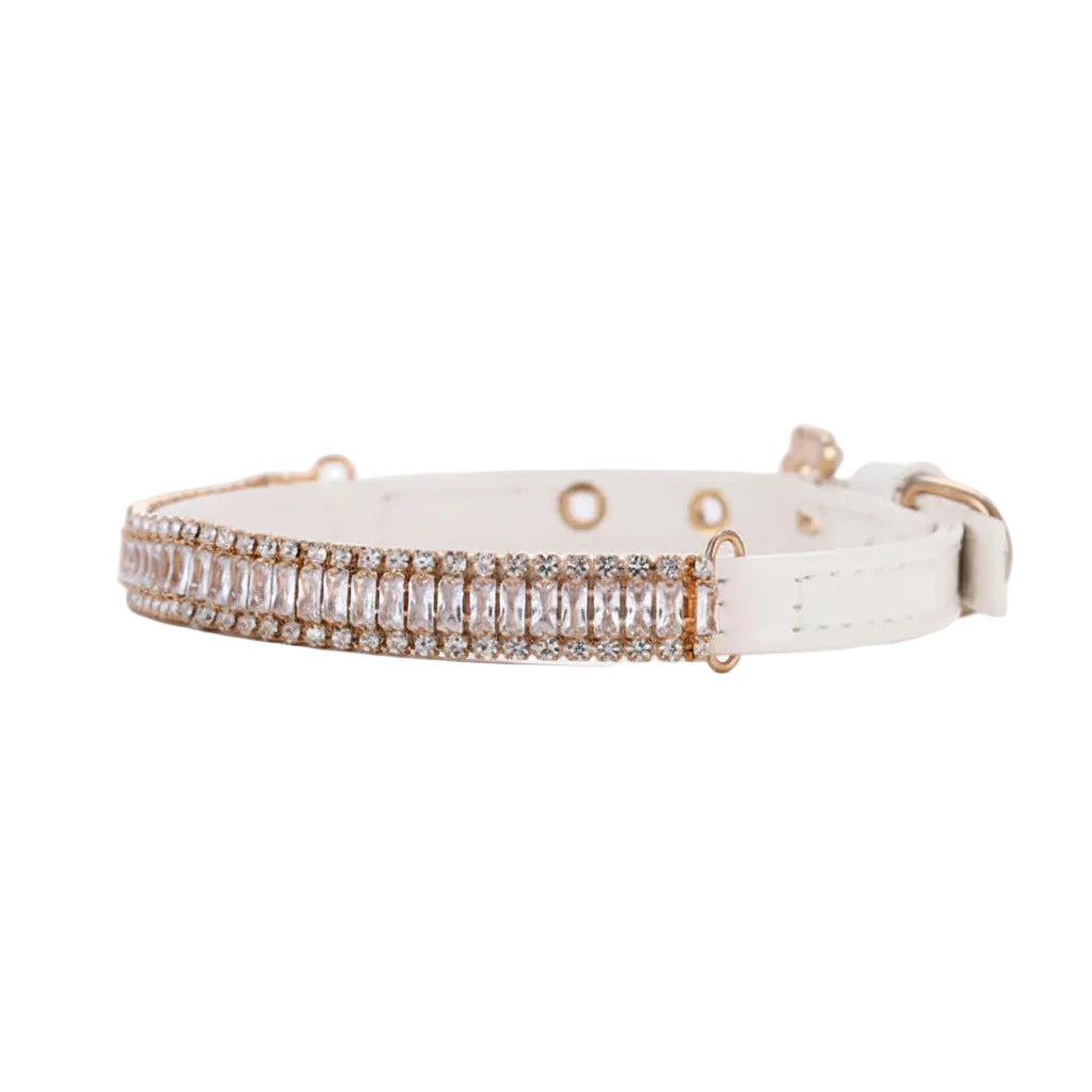 Pretty Posh Pets luxury rhinestone pet collar — angled side view of a white leather collar featuring a row of emerald-cut clear crystal baguette gemstones bordered by two rows of sparkling round rhinestones in gold settings, with adjustable eyelets and a gold D-ring on a white background.