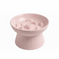 Blush pink ceramic raised slow feeder cat bowl with ribbed pedestal base and heart-center ridge pattern, white background
